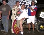 Mike McClelland shows a little leg in American Bank of Oklahoma ASCS Sooner Region victory lane after his son, Sean McClelland, rallied from the ninth row to make a last corner pass for the win in Saturday night's 25-lap feature at Creek County Speedway